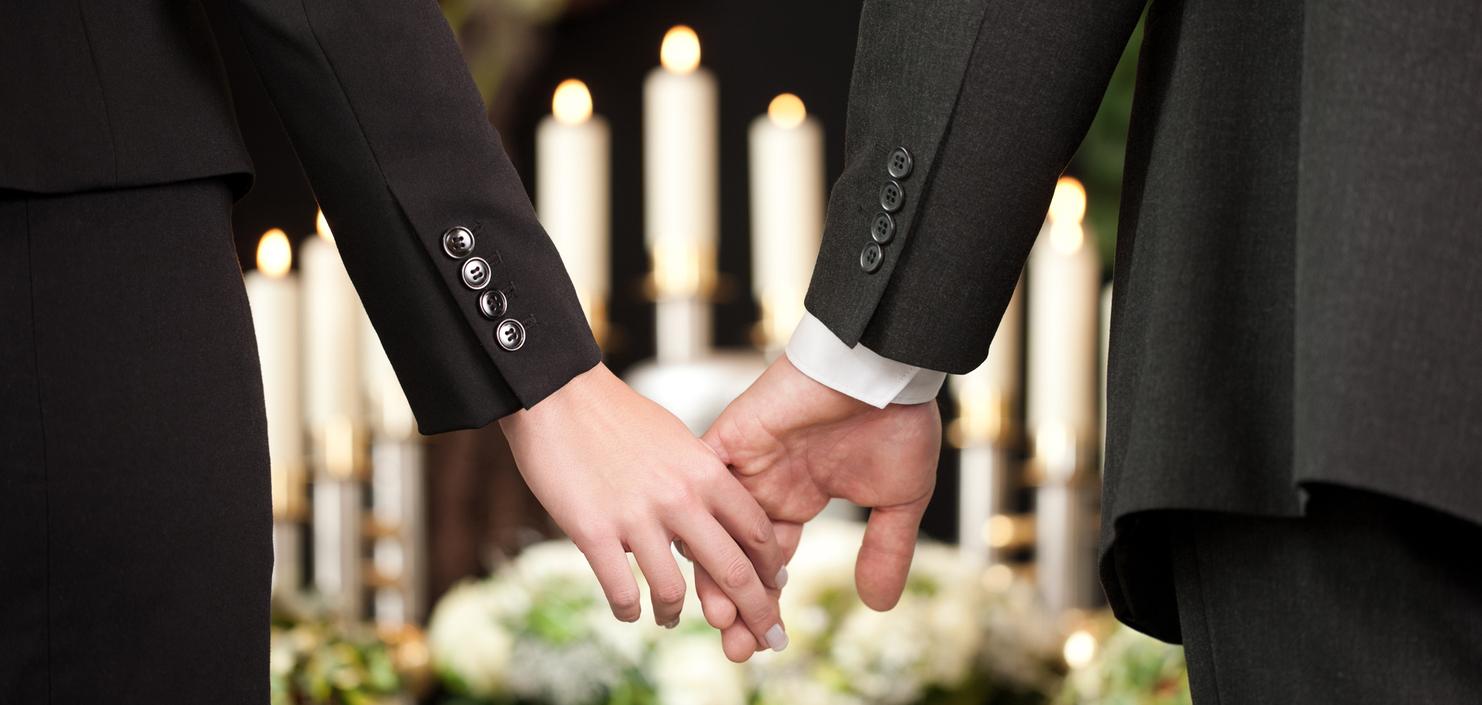 Hände eines Paares halten sich, umgeben von Kerzen und Blumenarrangements, in festlicher Atmosphäre.